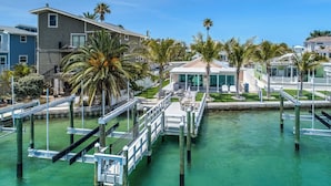 A waterfront property with a dock, palm trees, and a building with a covered patio.