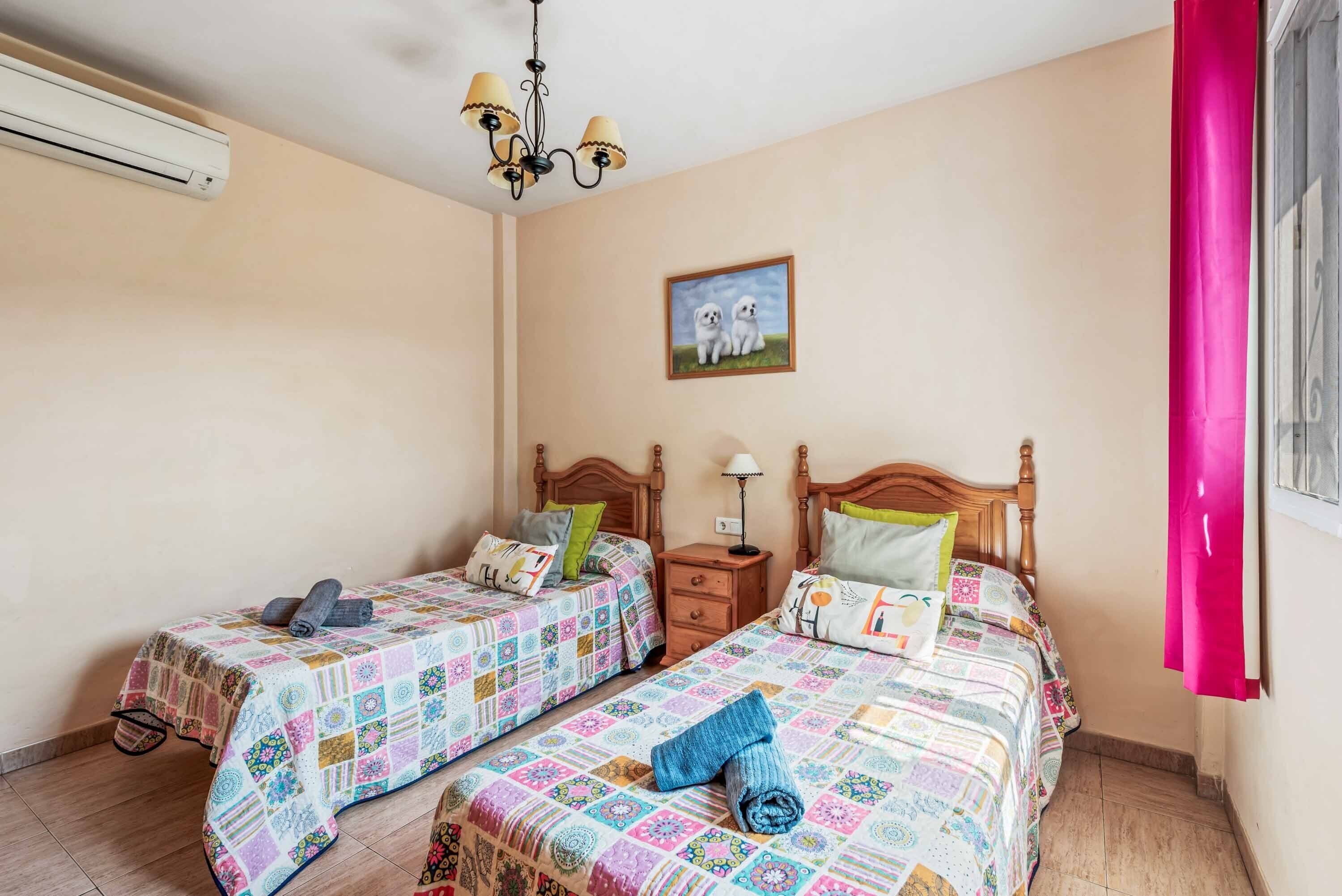 A bedroom with two beds, a wooden headboard, a nightstand, a lamp, and a picture on the wall.