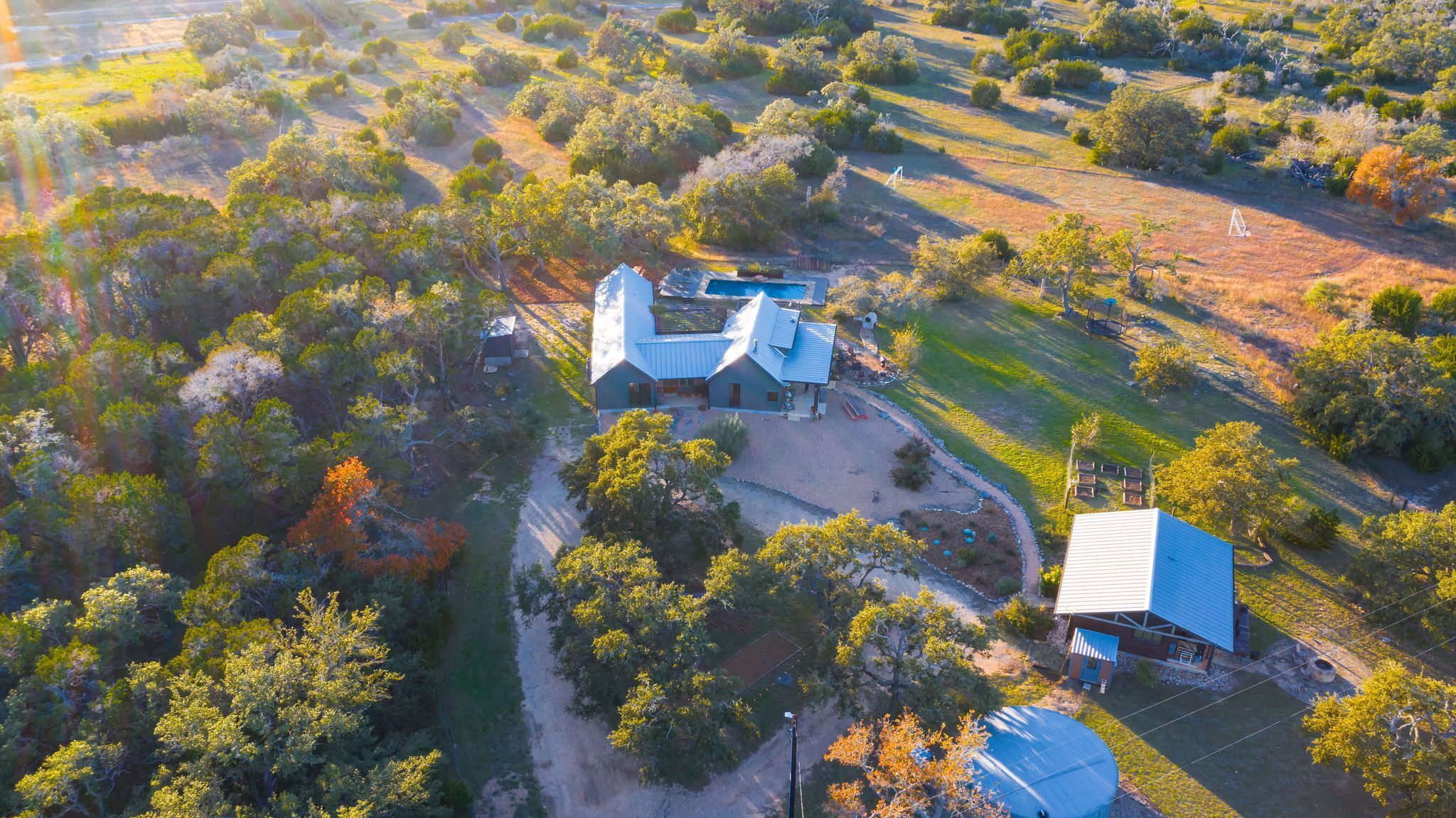 An aerial view of a property with a main house, a smaller building, and a large circular water tank.