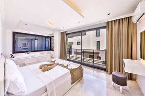 Ein modernes Hotelzimmer mit einem großen Bett, einem Badezimmer mit Waschbecken und einem Balkon mit Blick auf die Stadt.