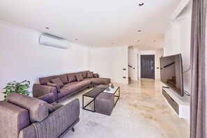 Ein modernes Wohnzimmer mit einem Ecksofa, einem Couchtisch und einem an der Wand befestigten Flachbildfernseher.