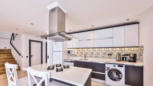 Una cucina moderna con isola centrale, elettrodomestici integrati e decorazioni a motivi sulla parete.