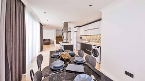 Zona pranzo moderna con tavolo in marmo, sedie grigie e isola centrale con forno a microonde.