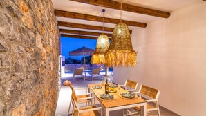 Un comedor con pared de piedra, vigas de madera y lámparas colgantes.