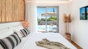Un dormitorio con una cama grande, vista a una piscina exterior y puerta corrediza de vidrio.