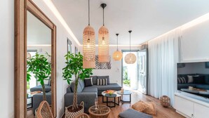 Una sala de estar moderna con un sofá gris, muebles de mimbre y un espejo grande.