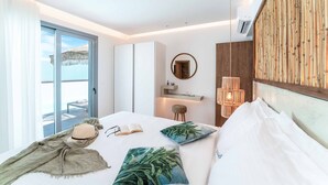 Habitación de hotel moderna con una cama grande, vistas a la playa, una pared de bambú y un pequeño escritorio con una lámpara.