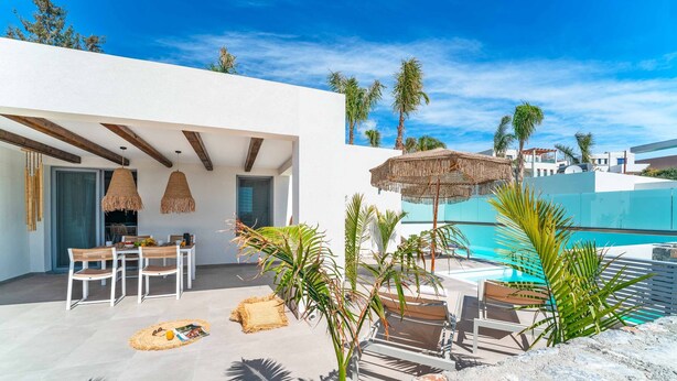 Un patio moderno al aire libre con piscina, zona de comedor y sillas de descanso.