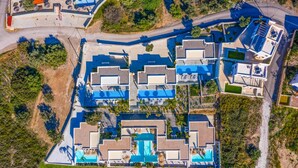 Vista aérea de un resort con varias edificaciones, una piscina central y follaje circundante.
