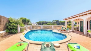 Una piscina con lettini e una zona patio coperta.