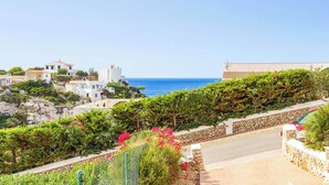 Una zona residenziale costiera con muri in pietra, una strada pavimentata e edifici con balconi vista mare.