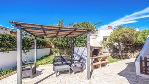 An outdoor patio with a pergola, wicker furniture, and a stone floor. - Villa Chiquita - Three Bedroom Villa, Sleeps 4 (Cala en Porter)