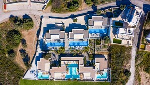 Vue aérienne d’un complexe hôtelier comprenant plusieurs bâtiments, une piscine centrale et de nombreux espaces verts.