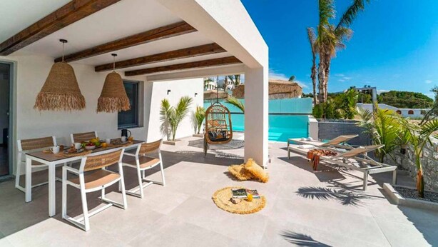 Une terrasse extérieure comprenant un espace repas, des chaises longues et une piscine.