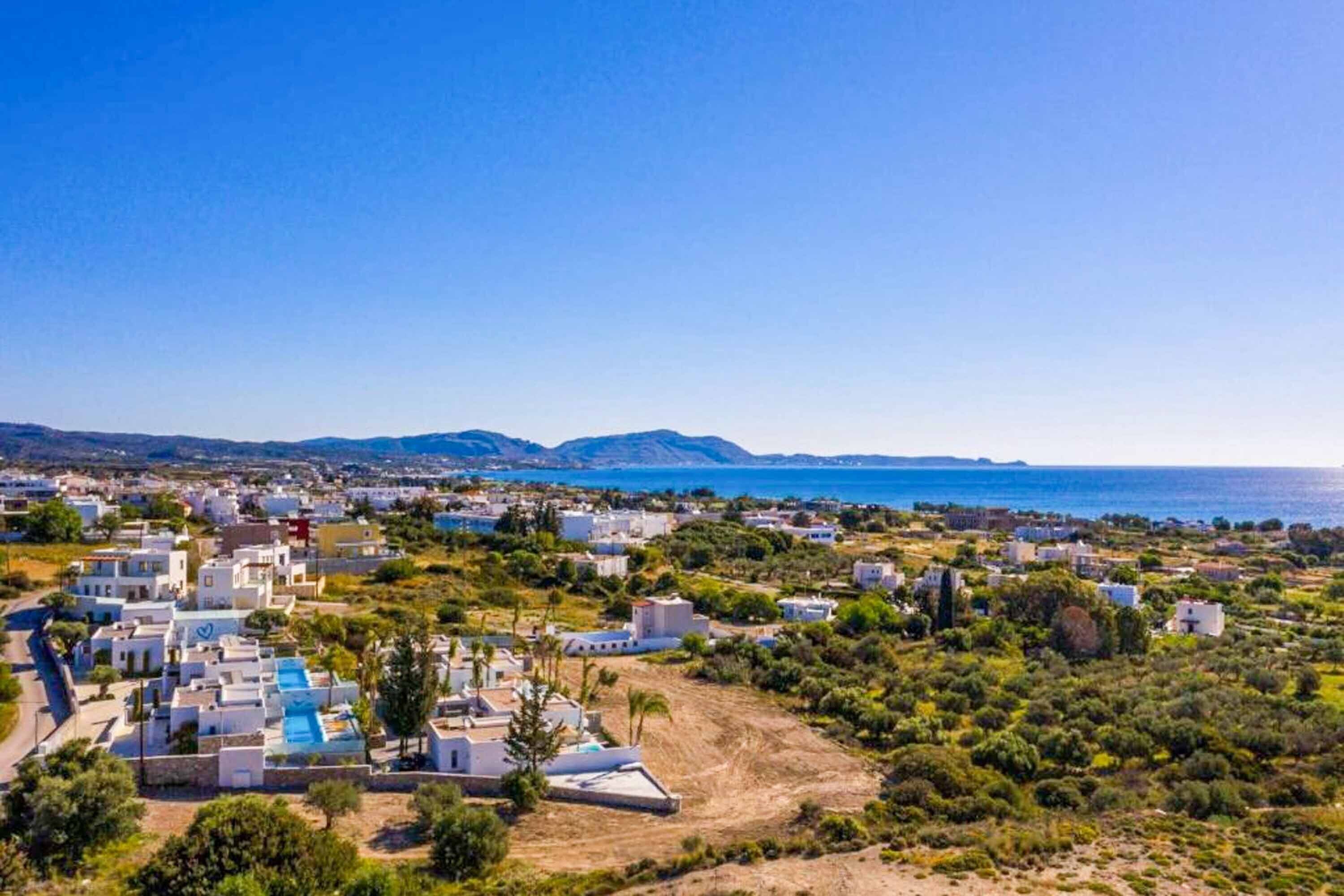 Una cittadina costiera con edifici bianchi, cielo azzurro limpido e vista sul mare.