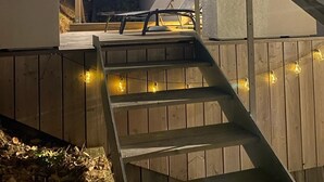A wooden staircase with a handrail, leading up to a deck area.