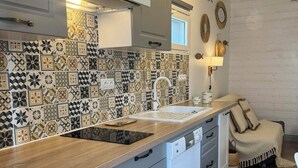 A modern kitchen with patterned backsplash, built-in dishwasher, and wooden countertop.