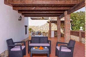 Eine Terrasse im Freien mit Korbmöbeln, einer Steinmauer und einem gefliesten Boden.