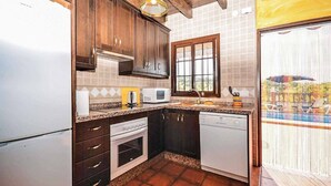 A kitchen with dark wooden cabinets, a white refrigerator, a microwave, a toaster, and a dishwasher. - Villa Cortijo Algarrobo (Frigiliana)