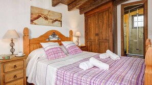 A neatly made bed with a checkered bedspread, wooden headboard, and two bedside lamps. - Villa Cortijo Algarrobo (Frigiliana)