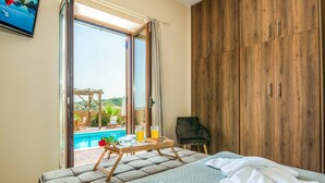 Quarto com cama, guarda-roupa de madeira, cadeira e bandeja de café da manhã com suco de laranja e doces.
