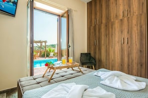 Ein Schlafzimmer mit einem Bett, einem Holzschrank, einem Stuhl und einem Frühstückstisch mit Orangensaft und Gebäck.