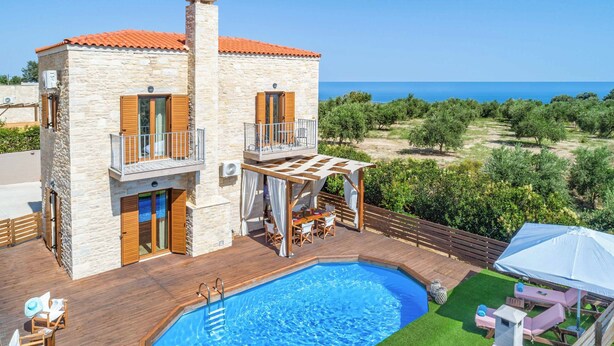 A two-story stone building with a swimming pool, outdoor seating, and a view of the sea. - Villa Ourania Klio - Two Bedroom Villa, Sleeps 4 (Crete)