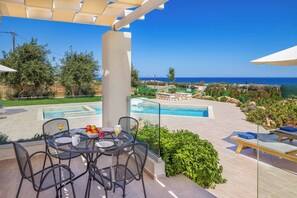 Eine Terrass mit Pool, Esstisch und Stühlen mit Blick auf eine malerische Landschaft.