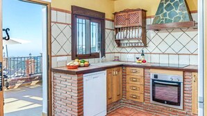 A compact kitchen with a dishwasher, oven, and a small cabinet with a decorative tile backsplash.