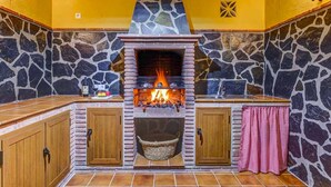 A stone fireplace with a fire, wooden cabinets, and a stone wall.