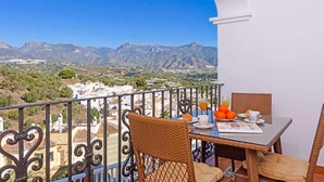 Un balcón con una mesa dispuesta para el desayuno, con vistas a un paisaje montañoso.