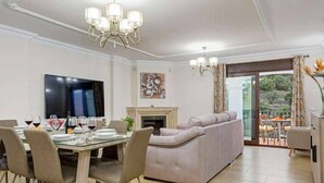 Una sala de estar moderna con comedor, chimenea y un amplio ventanal con cortinas.