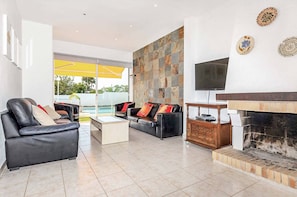 A modern living room with a fireplace, leather sofas, a coffee table, and a TV mounted on the wall. - Casa do Engenho - Three Bedroom Villa, Sleeps 6 (Vale Rebelho)