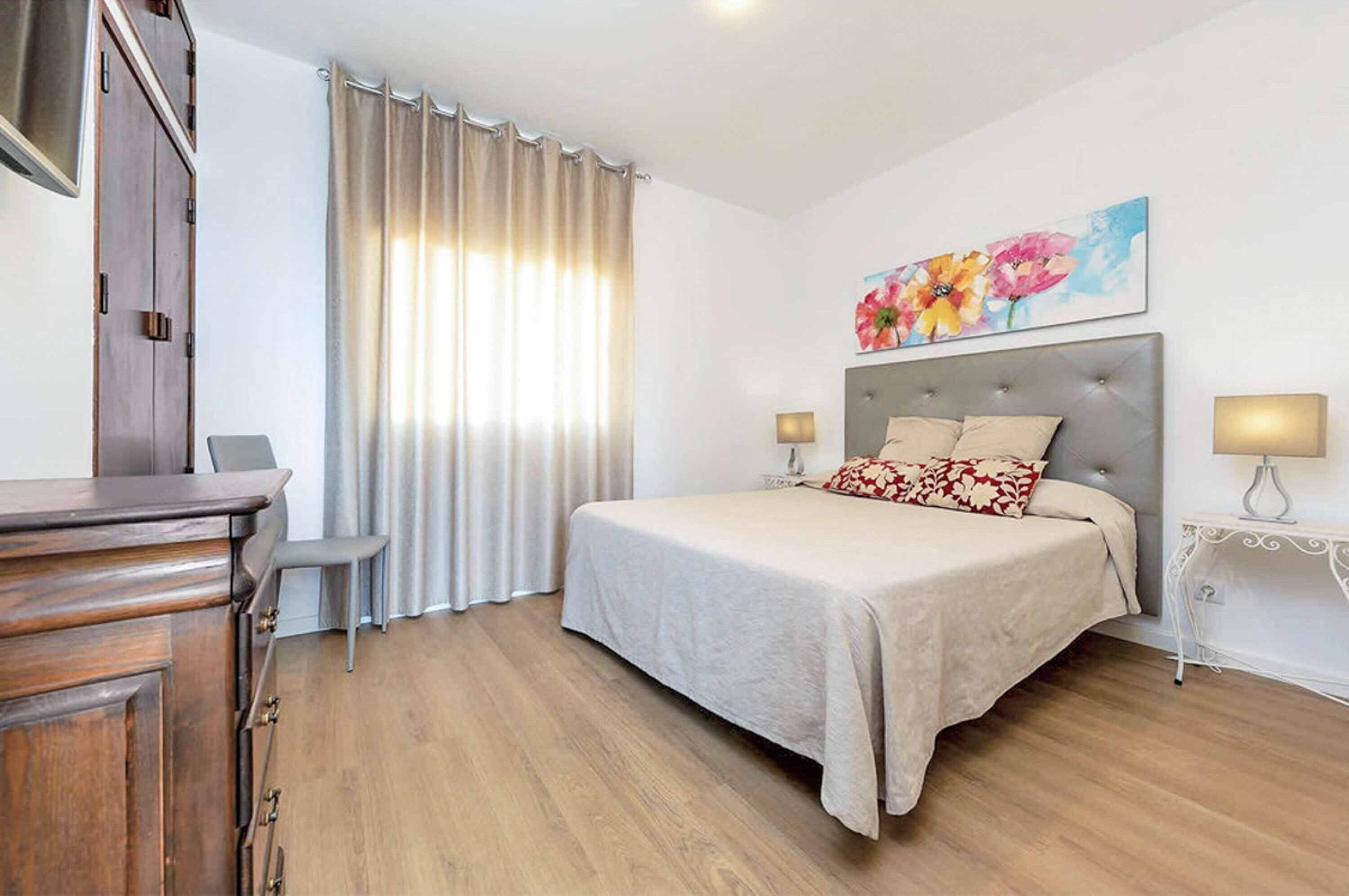 Un dormitorio con cama, mesitas de noche, escritorio y silla.