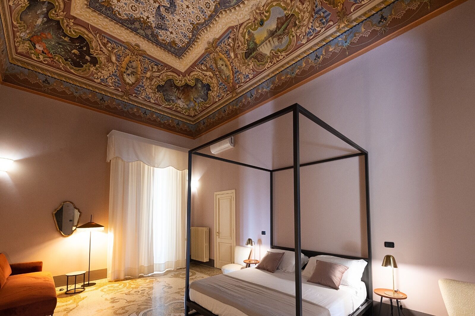 Una cama con dosel de diseño moderno, un techo grande y ornamentado, y un clásico candelabro.