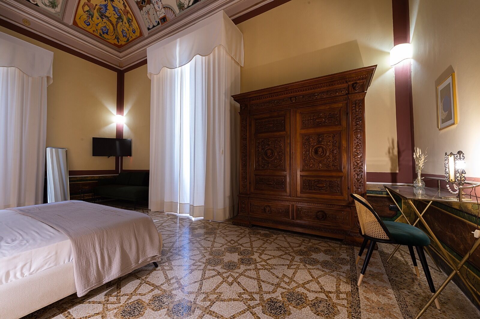 Una habitación de hotel con cama, escritorio, silla y un gran armario de madera.