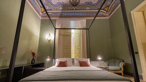Een hemelbed met baldakijn, een nachtkastje met lamp, een stoel en een spiegel.