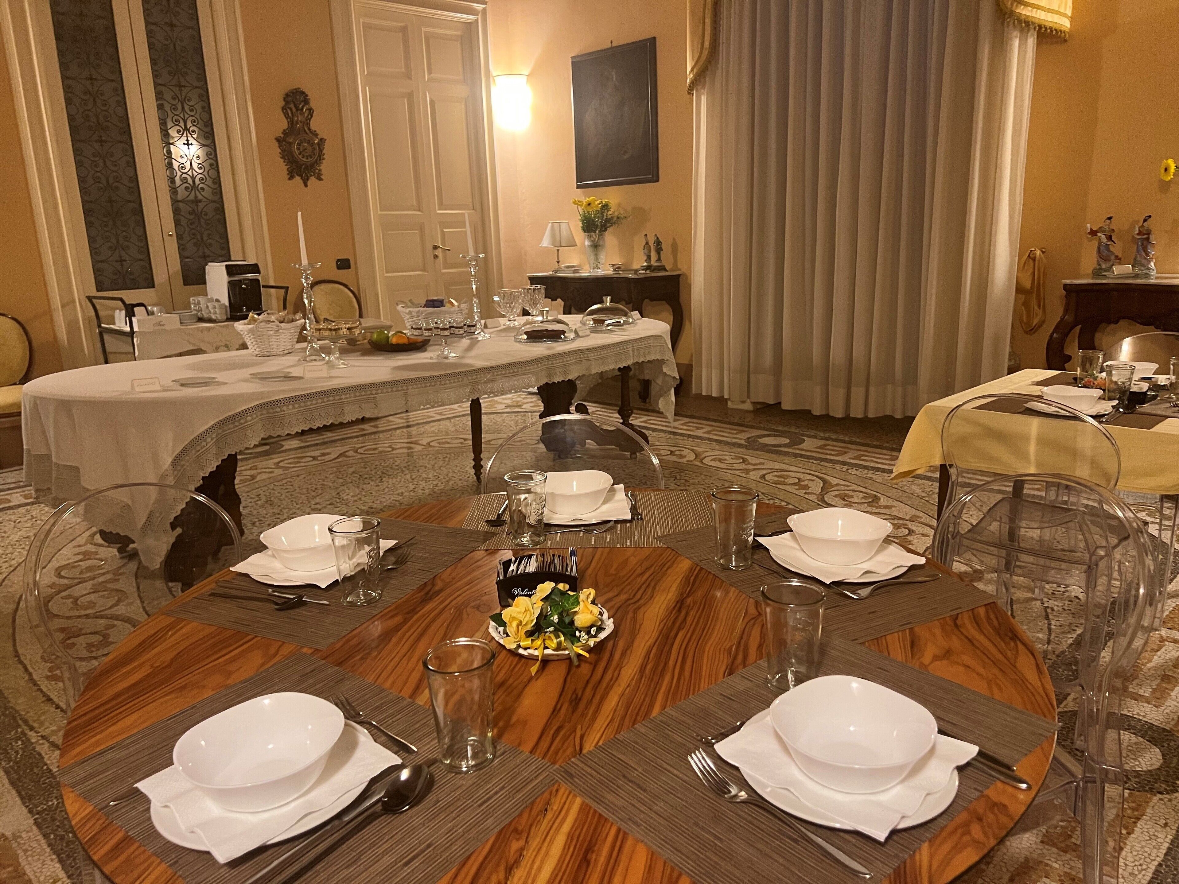 Ein formeller Speisesaal mit einem großen runden Tisch, gedeckt für eine Mahlzeit, umgeben von Stühlen.