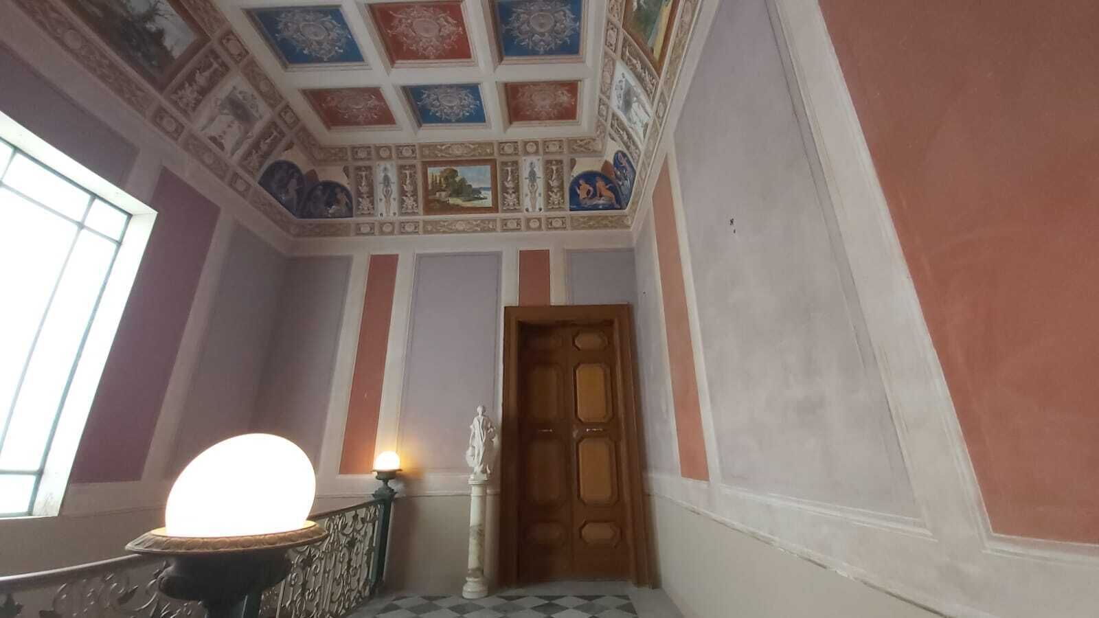 Un pasillo con una puerta de madera, una lámpara y un suelo estampado.
