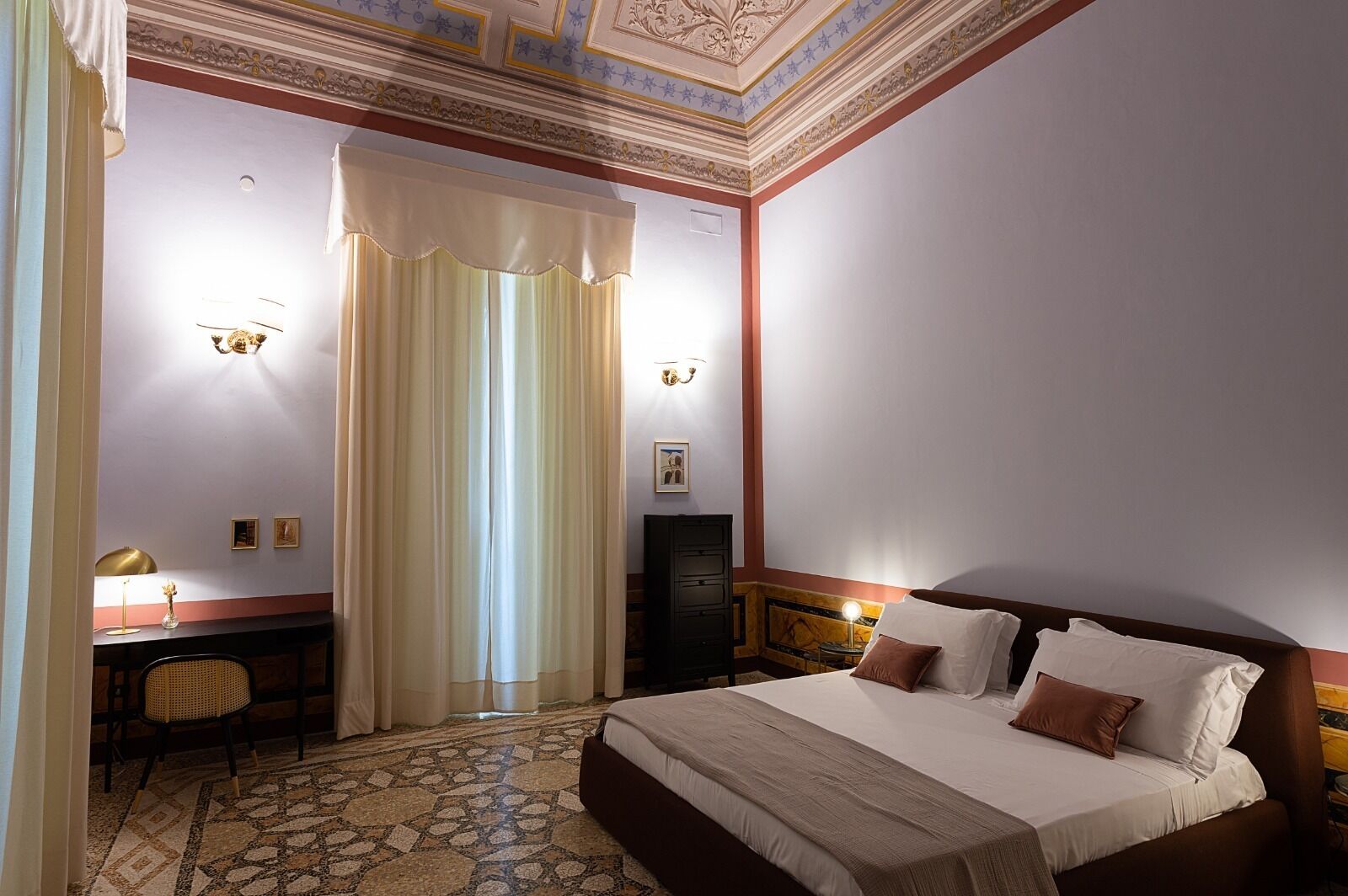 Een hotelkamer met een groot bed, een bureau met lamp, een stoel en een kledingkast.