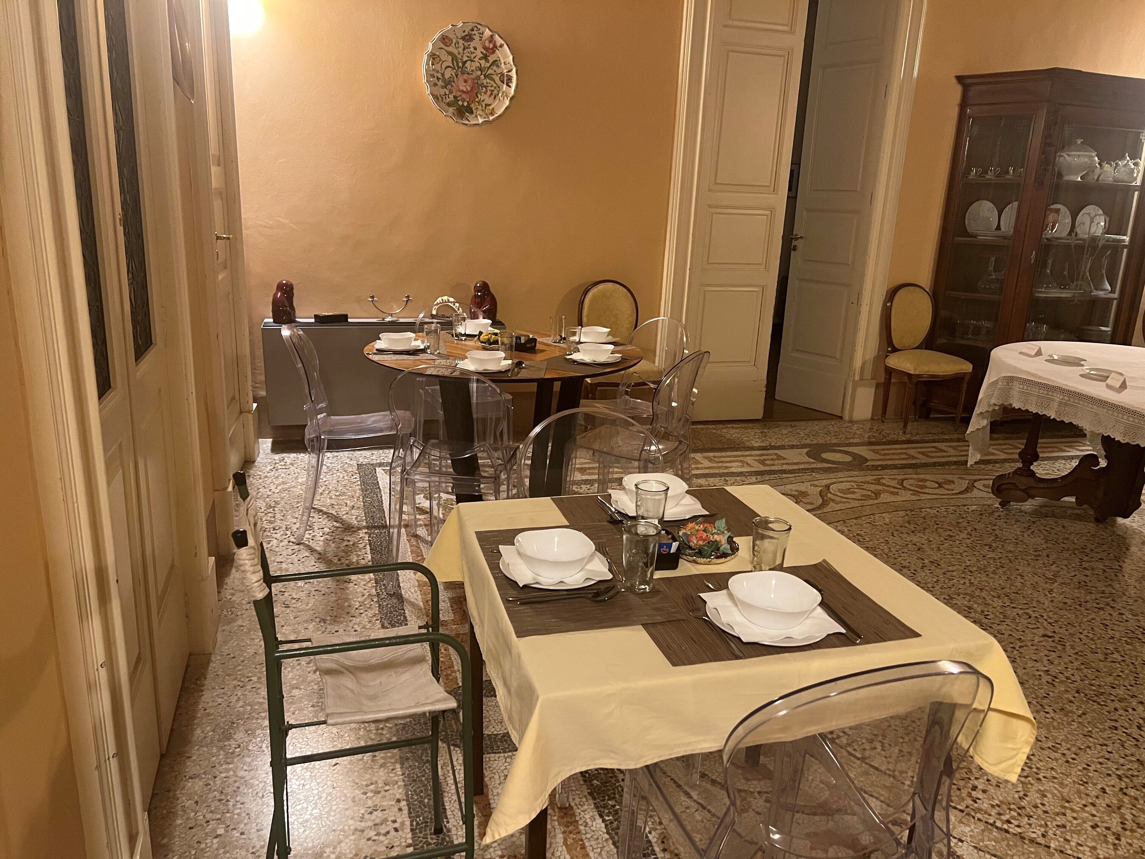 A dining area with a table set for four, clear chairs, a cabinet with glass doors, and a patterned rug.