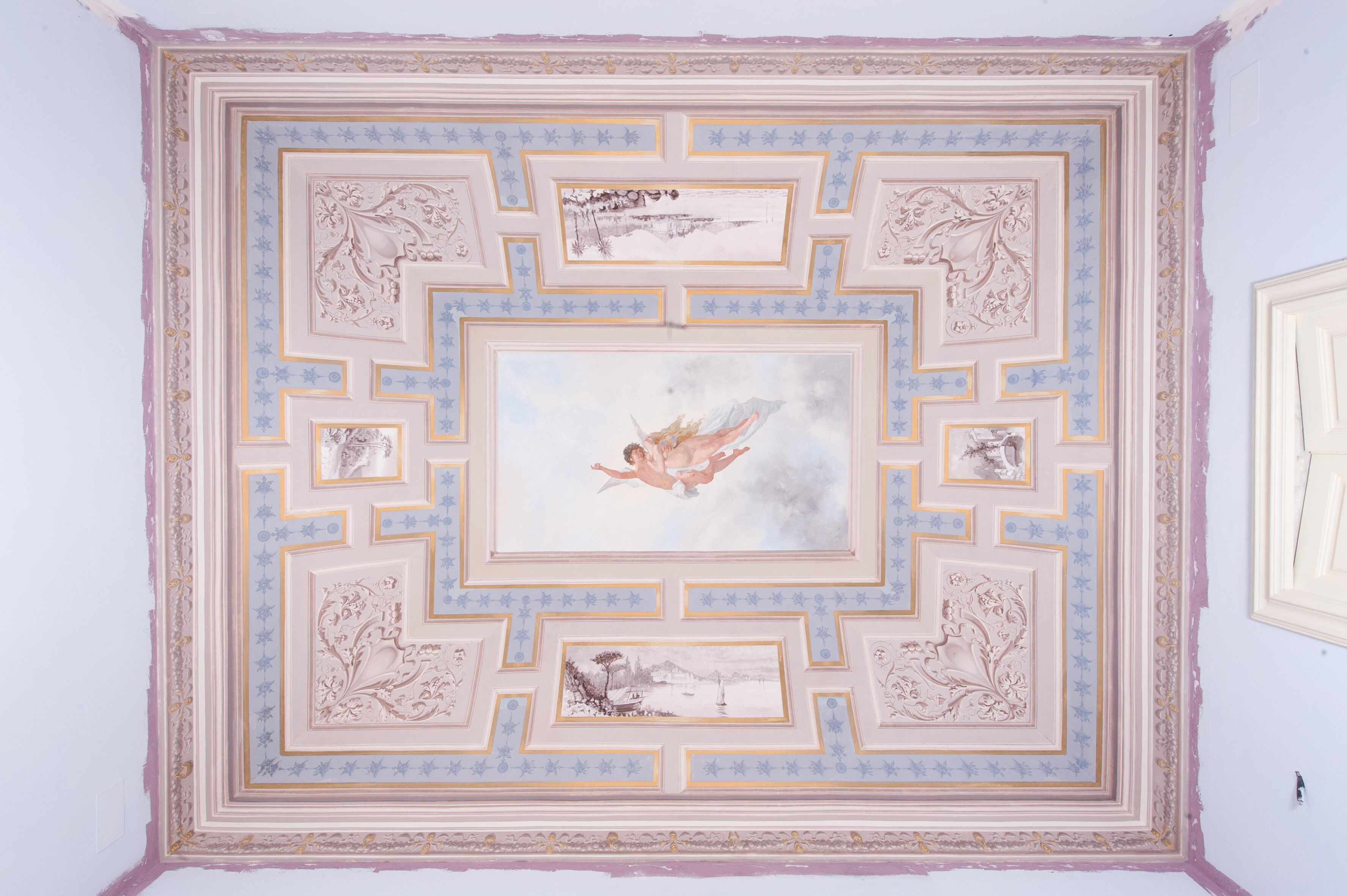 A ceiling with a central mural of a figure, surrounded by ornate geometric patterns and floral motifs.