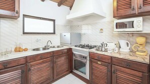 A kitchen with wooden cabinets, a gas stove, a microwave, and a sink. - Casa Nomanico - Two Bedroom Villa, Sleeps 4 (Estoi)