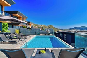 A rooftop pool with lounge chairs and a glass balustrade.