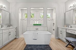 Un baño moderno con una bañera independiente, tocador con espejo y un pequeño banco.