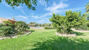 A well-maintained garden with a pool, stone building, and lush greenery. - Ca l Berros - Three Bedroom Villa, Sleeps 6 (Alcúdia)