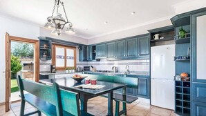 A modern kitchen with teal cabinetry, a central island, and a dining area with benches. - Ca l Berros - Three Bedroom Villa, Sleeps 6 (Alcúdia)