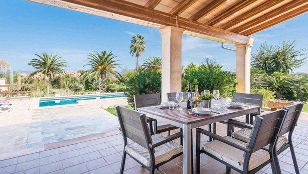 An outdoor patio with a pool, surrounded by palm trees and greenery. - Ca l Berros - Three Bedroom Villa, Sleeps 6 (Alcúdia)
