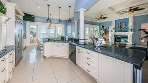 A spacious kitchen with a large island, white cabinetry, and a view to the outside.