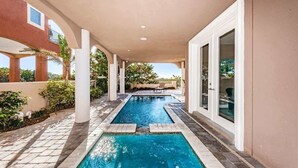 A pool area with two rectangular pools, white columns, and a covered walkway.